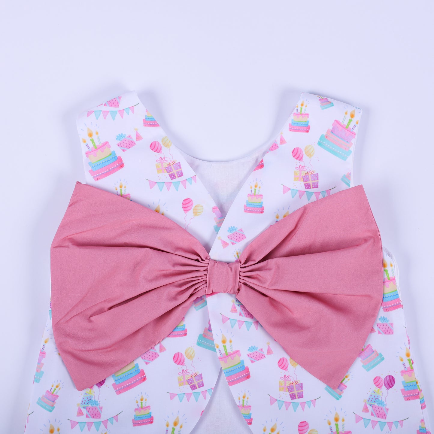 Detailed close up of the beautiful oversized solid pink statement bow on the back of the pastel birthday swing top.
