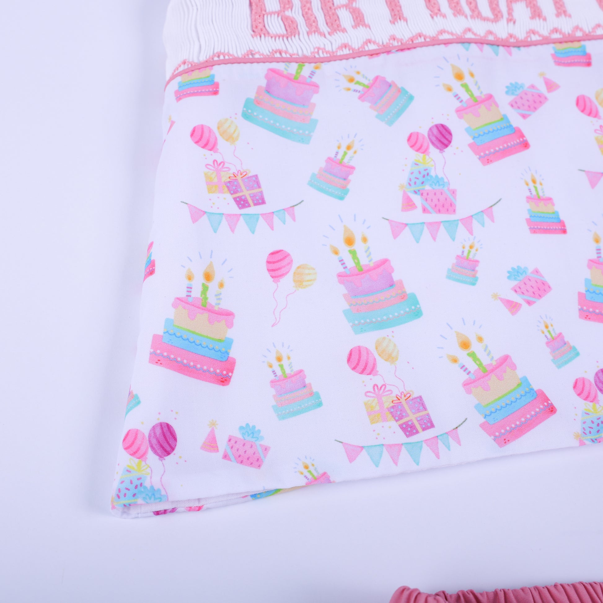 Close-up of the custom woven pastel fabric showing a print of birthday cakes, festive balloons, and small presents.