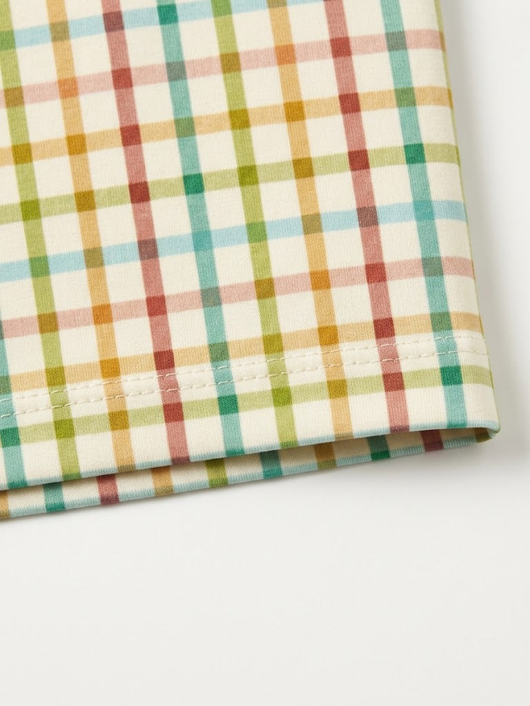 Close-up detail of soft pastel yellow, green, and orange fall plaid fabric hem.