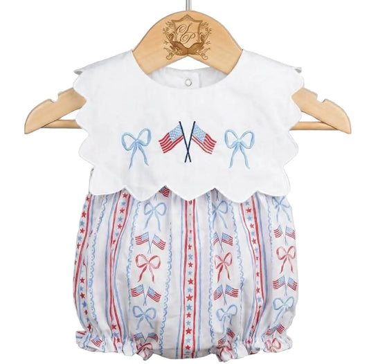 Patriotic Grandmillennial embroidered baby bubble on wooden hanger featuring scalloped collar with flag embroidery.