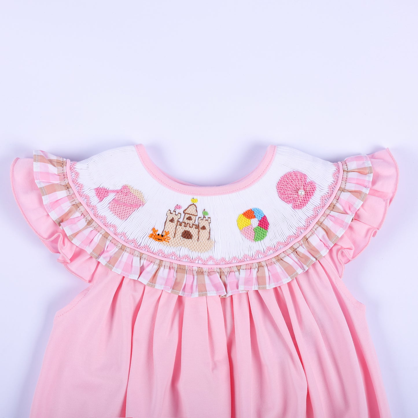 Detailed view of hand-smocked beach collar on a pink baby bubble with sandcastle embroidery and gingham ruffle.