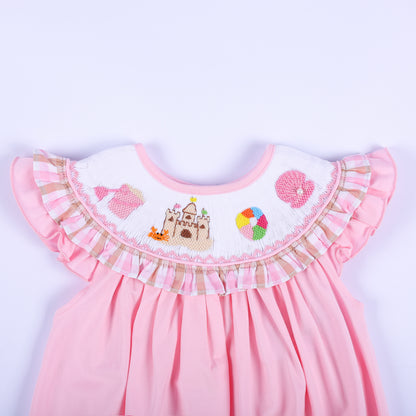 Detailed view of hand-smocked beach collar on a pink baby bubble with sandcastle embroidery and gingham ruffle.