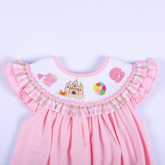 Detailed view of hand-smocked beach collar on a pink baby bubble with sandcastle embroidery and gingham ruffle.