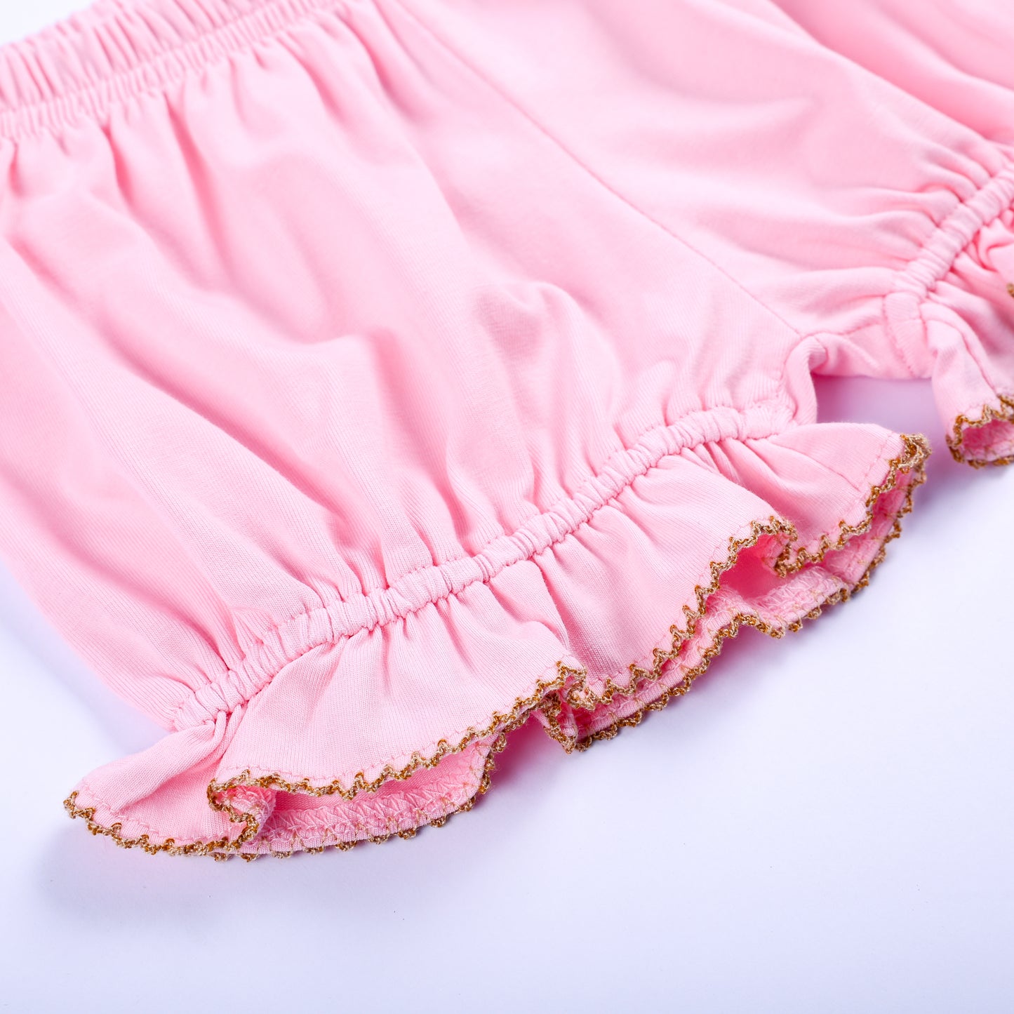 Close-up of pink bloomer shorts ruffle hem with decorative gold picot stitching for toddler girl set.