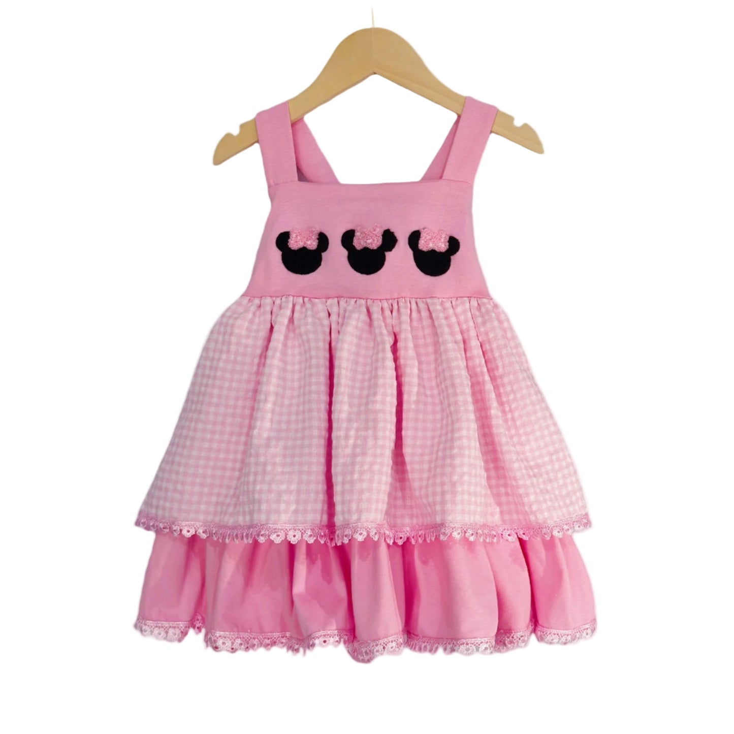 Pink Bow Mouse French Knot Dress with pink gingham tiered skirt and lace trim displayed on a wooden hanger.