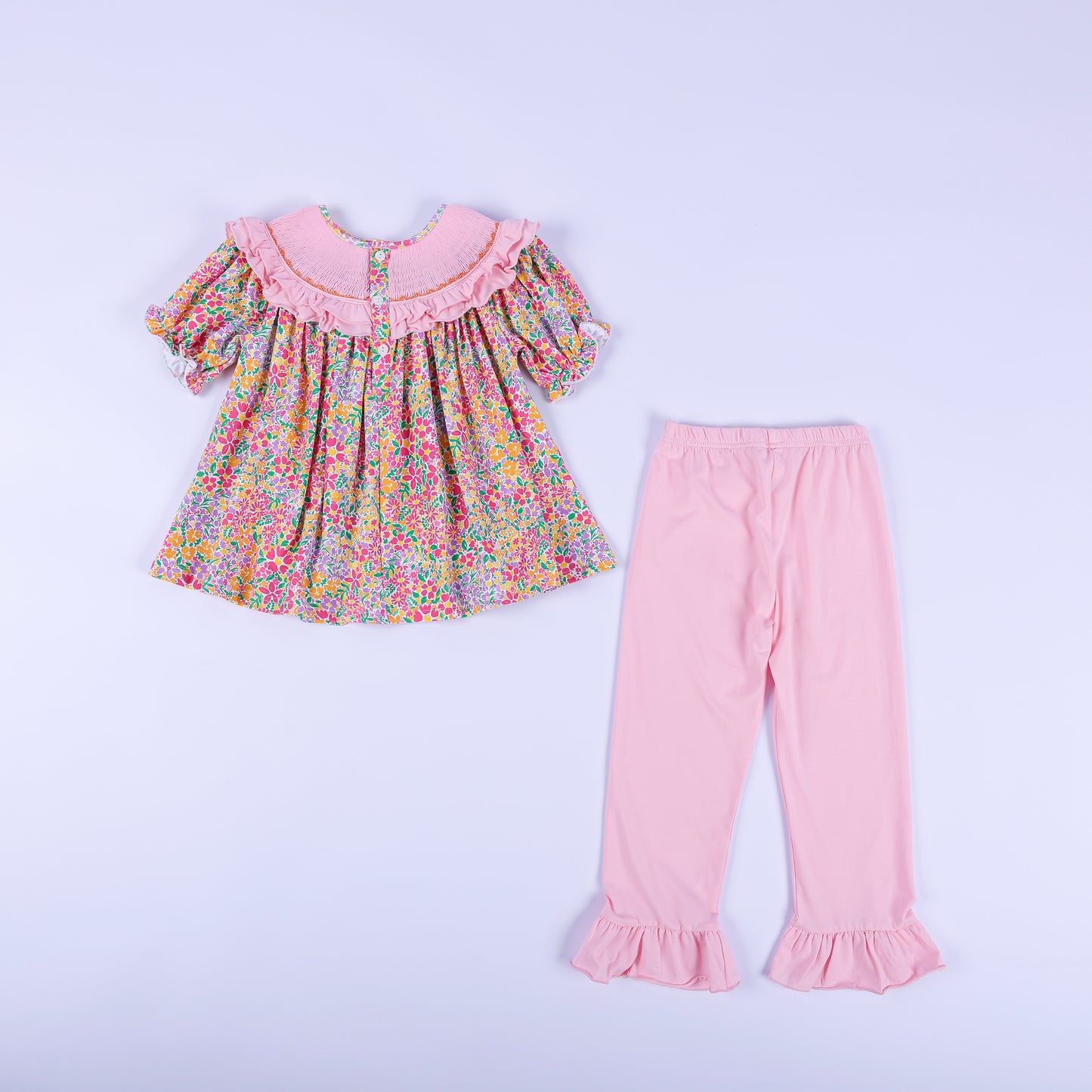 Back view of the girls boutique Thanksgiving outfit showing the button-back floral tunic top and pink ruffle pants.