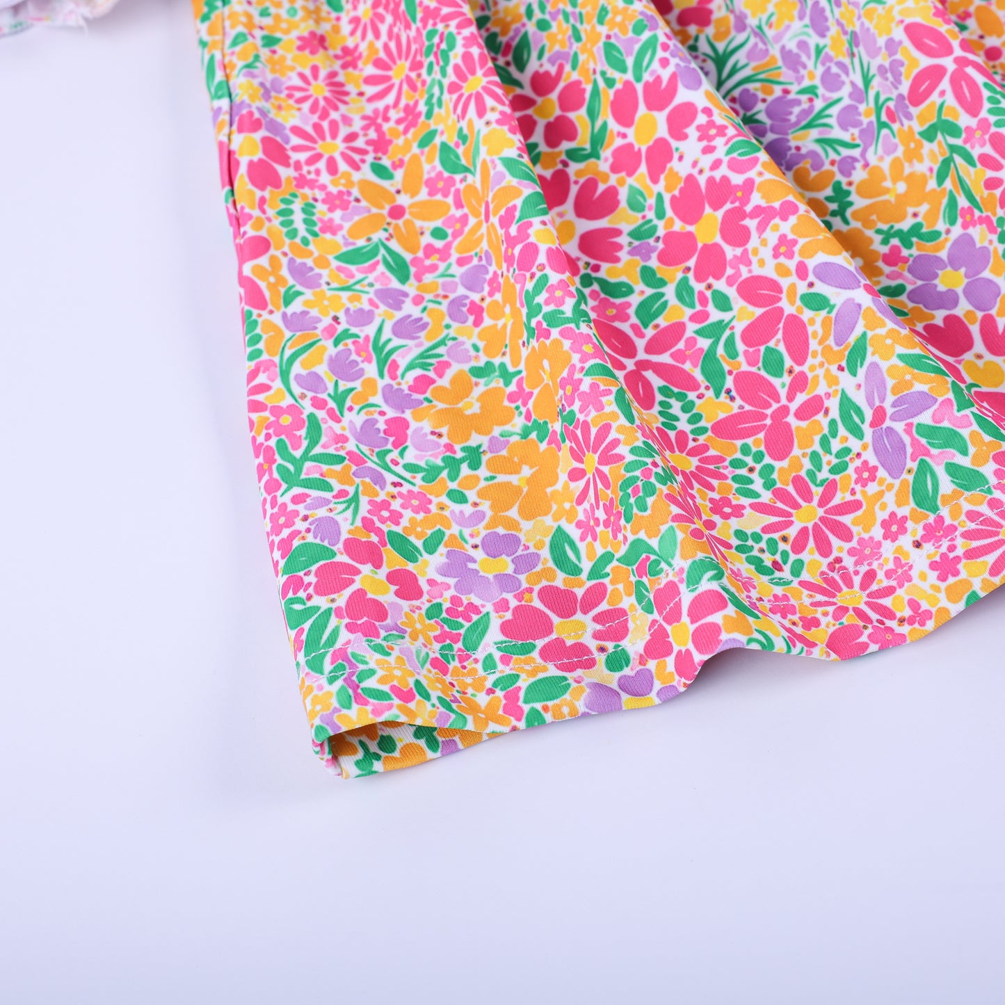 Close-up detail of the bright pink, orange, and yellow floral custom knit fabric print on the Thanksgiving tunic hem.