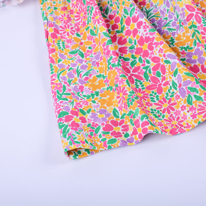 Close-up detail of the bright pink, orange, and yellow floral custom knit fabric print on the Thanksgiving tunic hem.