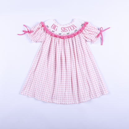 Front view of a pink gingham Big Sister dress with hand-smocked embroidered collar and ruffled puff sleeves.