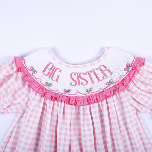 Close-up of hand-smocked white collar with pink Big Sister embroidery and floral accents on a gingham dress.