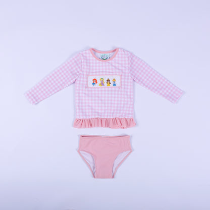 Front flat lay of girls pink gingham fairytale princess hand smocked two piece rash guard swimsuit with pink bottoms.