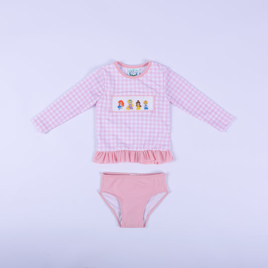 Front flat lay of girls pink gingham fairytale princess hand smocked two piece rash guard swimsuit with pink bottoms.