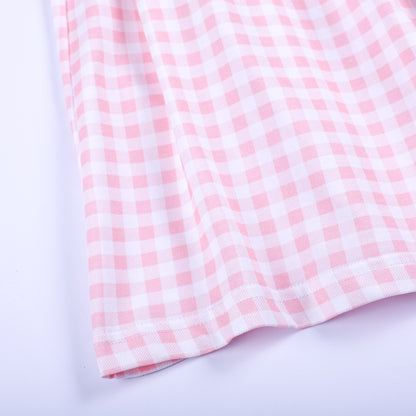 Close-up shot of the soft pink and white gingham check cotton fabric and hem detail on a smocked girl dress.