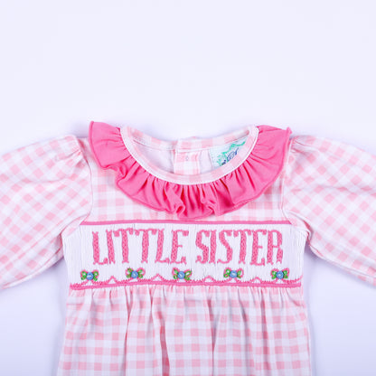 Close-up of pink gingham layette sleep sack showing hand embroidered Little Sister text and smocked bodice detail.