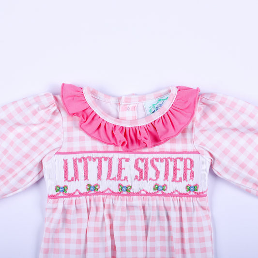 Close-up of pink gingham layette sleep sack showing hand embroidered Little Sister text and smocked bodice detail.