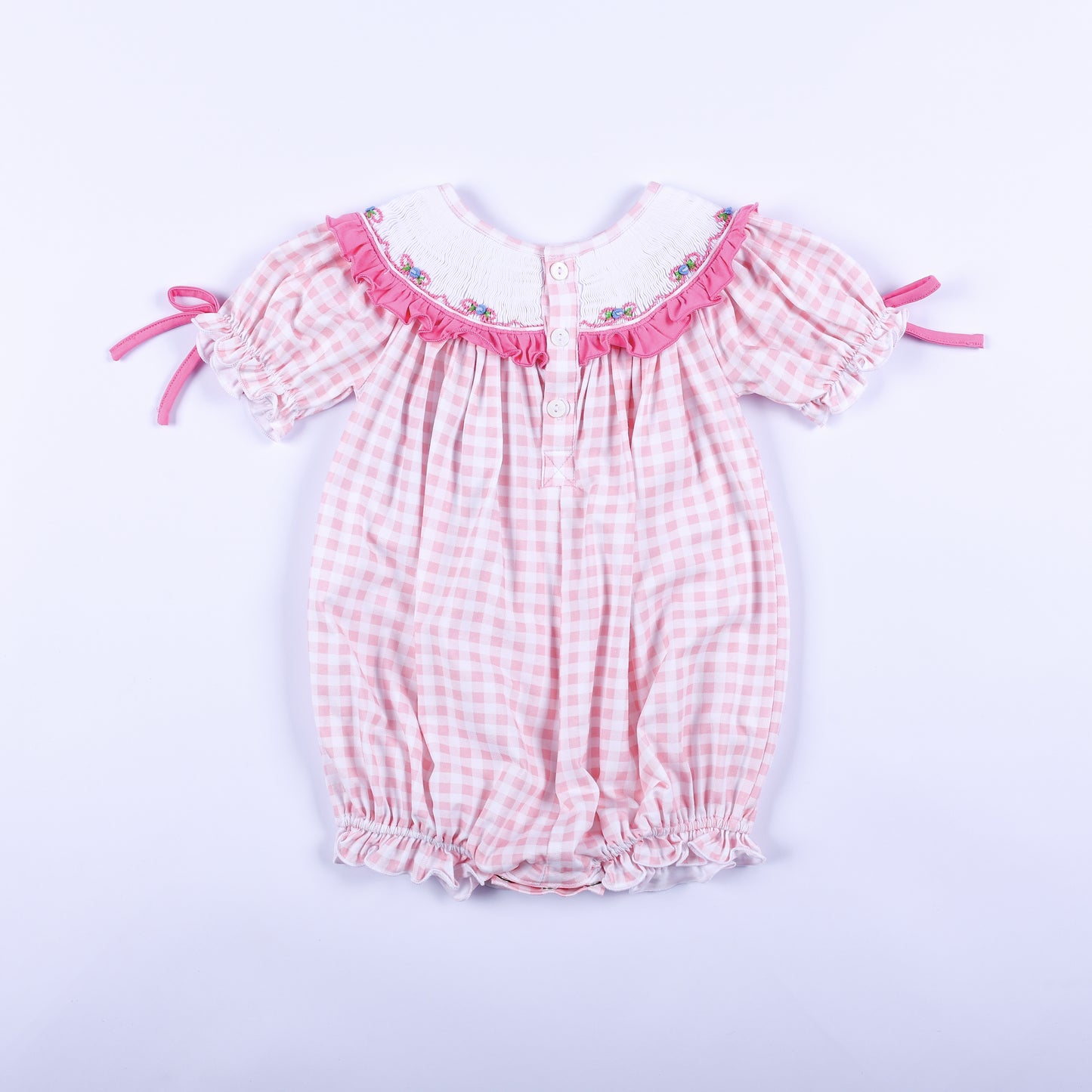 Full back view of baby girls pink gingham hand smocked Little Sister bubble romper showing button closures.