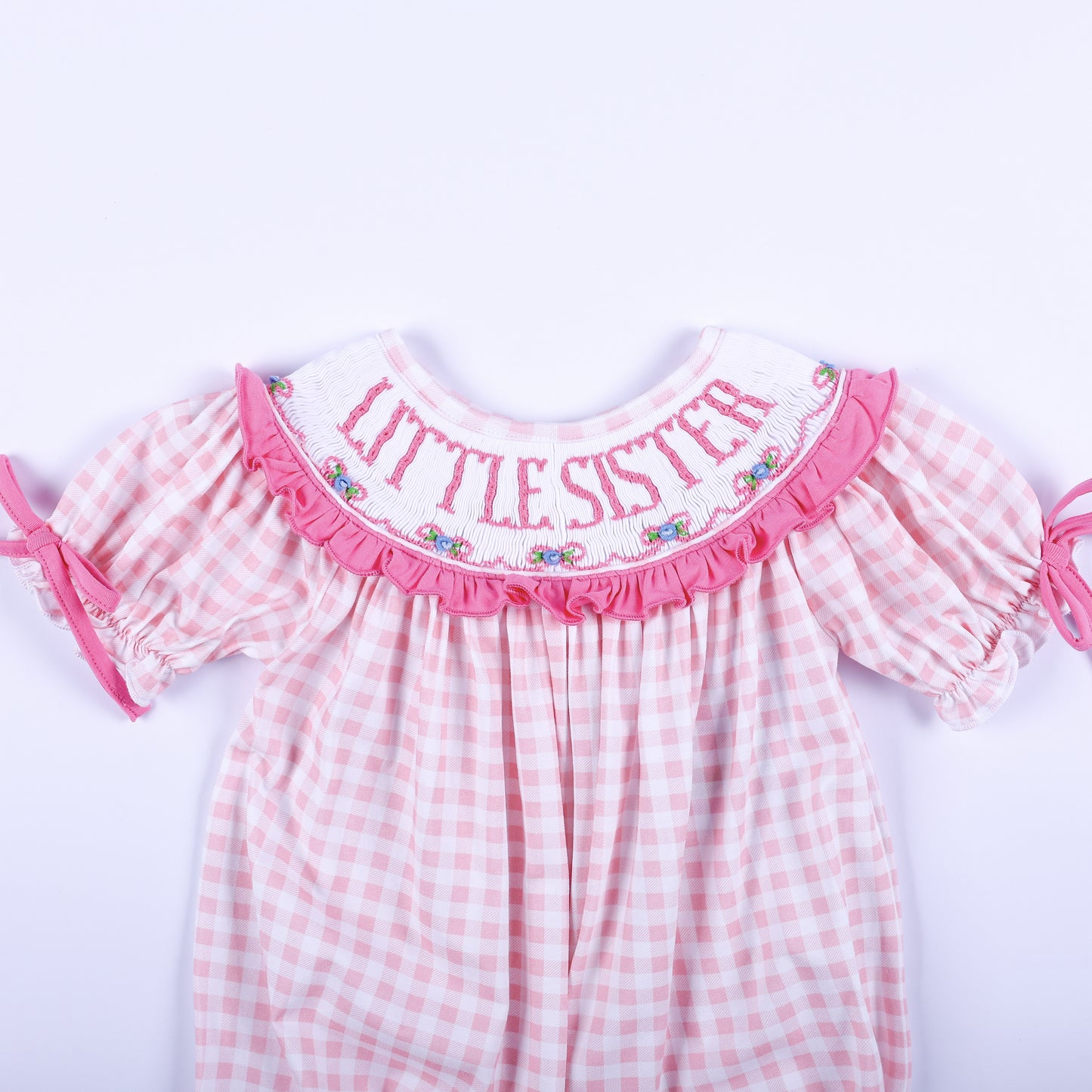 Close up of pink gingham baby bubble showing hand smocked collar with pink embroidered Little Sister lettering.