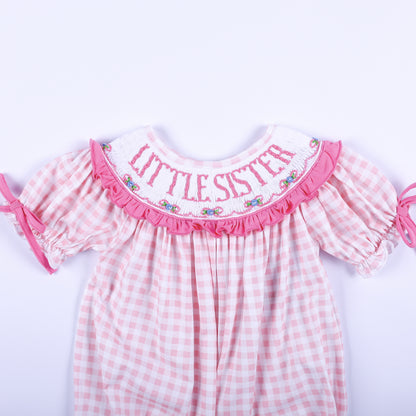 Close up of pink gingham baby bubble showing hand smocked collar with pink embroidered Little Sister lettering.