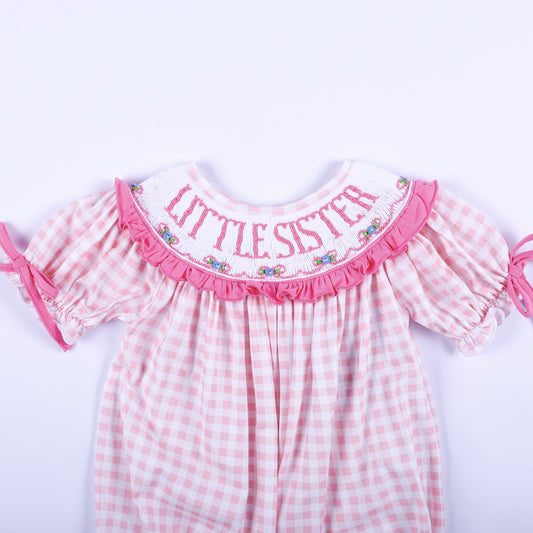Close up of pink gingham baby bubble showing hand smocked collar with pink embroidered Little Sister lettering.