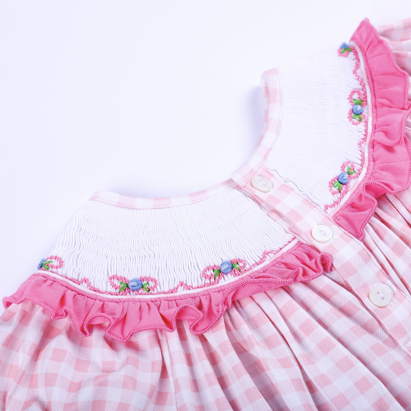 Close up of back button closure and ruffled neck collar on pink gingham hand smocked baby bubble outfit.