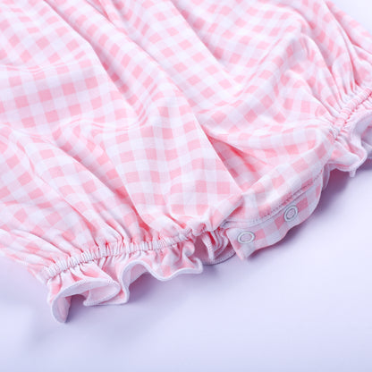 Bottom detail of baby girls pink gingham smocked bubble featuring ruffled leg openings and snap closures.