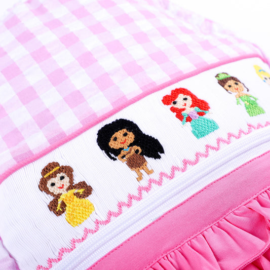 Detailed view of hand-smocked and hand-embroidered inclusive fairytale princess panel on pink backpack.