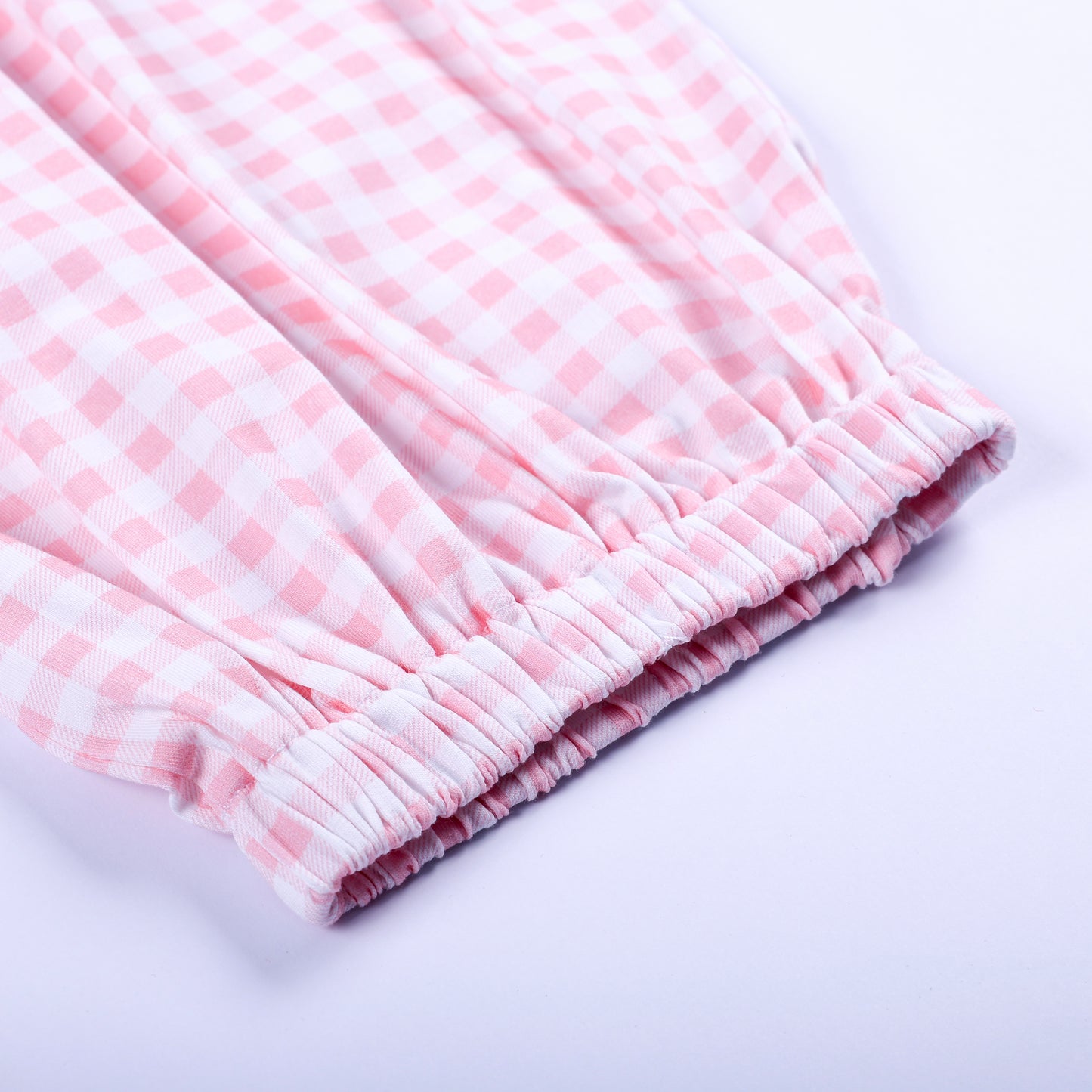 Close-up view of comfortable elastic bottom hem on pink gingham hand smocked Little Sister baby sleep sack.