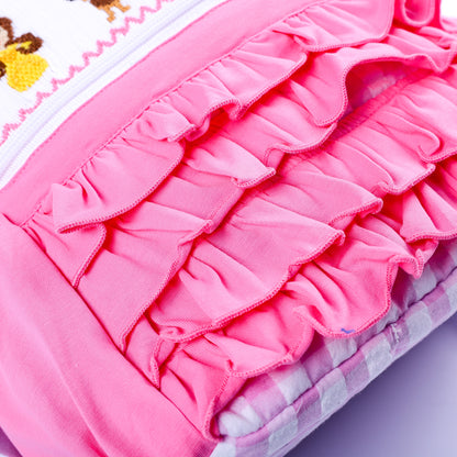 Close-up of layered pink fabric ruffles on front pocket of smocked fairytale princess backpack for girls.
