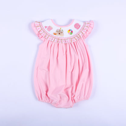 Front view of a pink hand-smocked baby bubble outfit featuring a ruffled beach-themed embroidered collar.