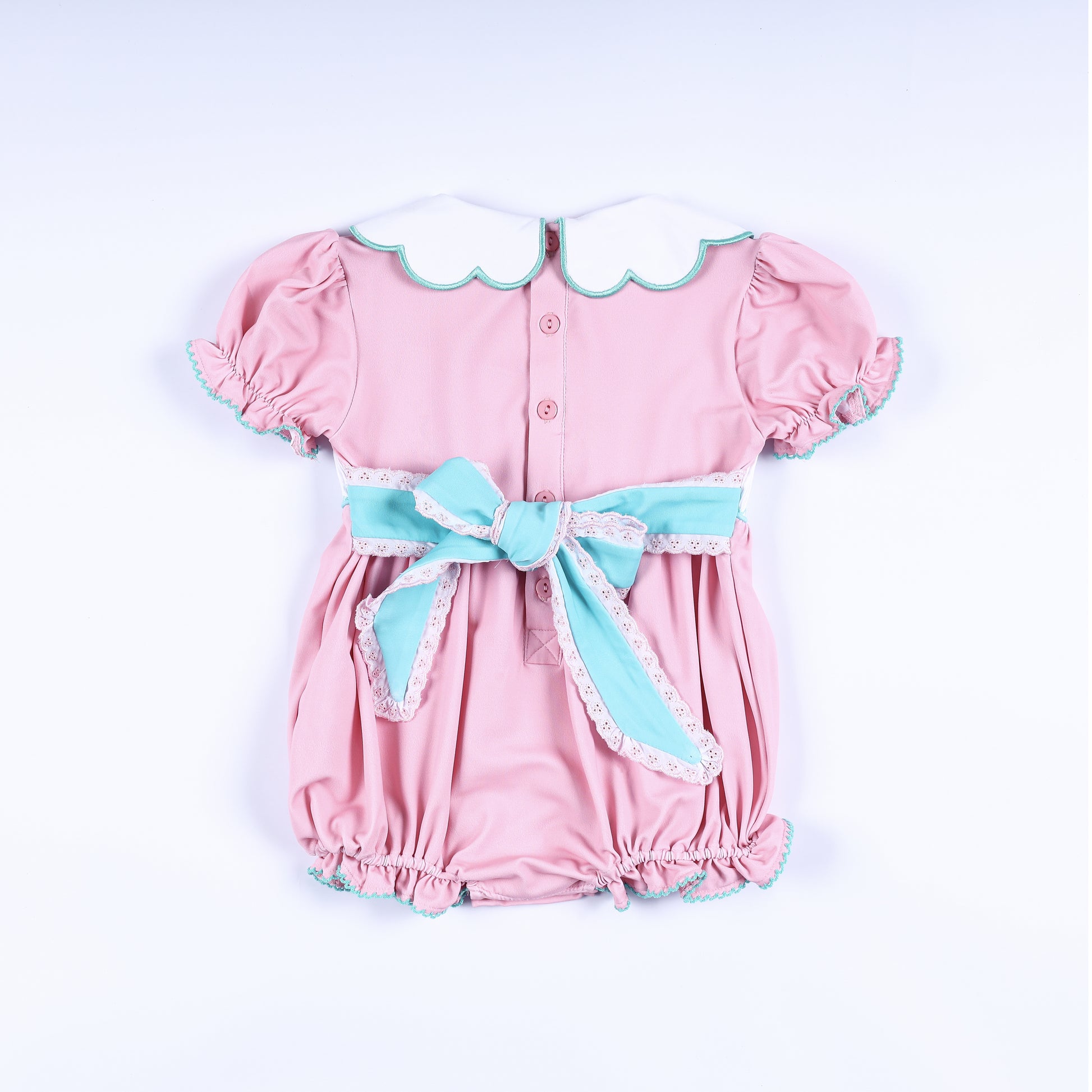 Back view of pink hand smocked bubble outfit with aqua sash bow and scalloped Peter Pan collar for baby girls.