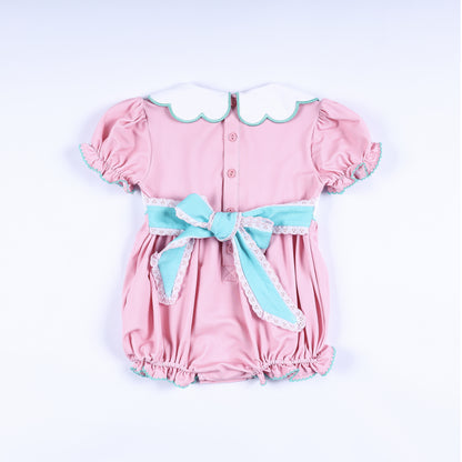 Back view of pink hand smocked bubble outfit with aqua sash bow and scalloped Peter Pan collar for baby girls.