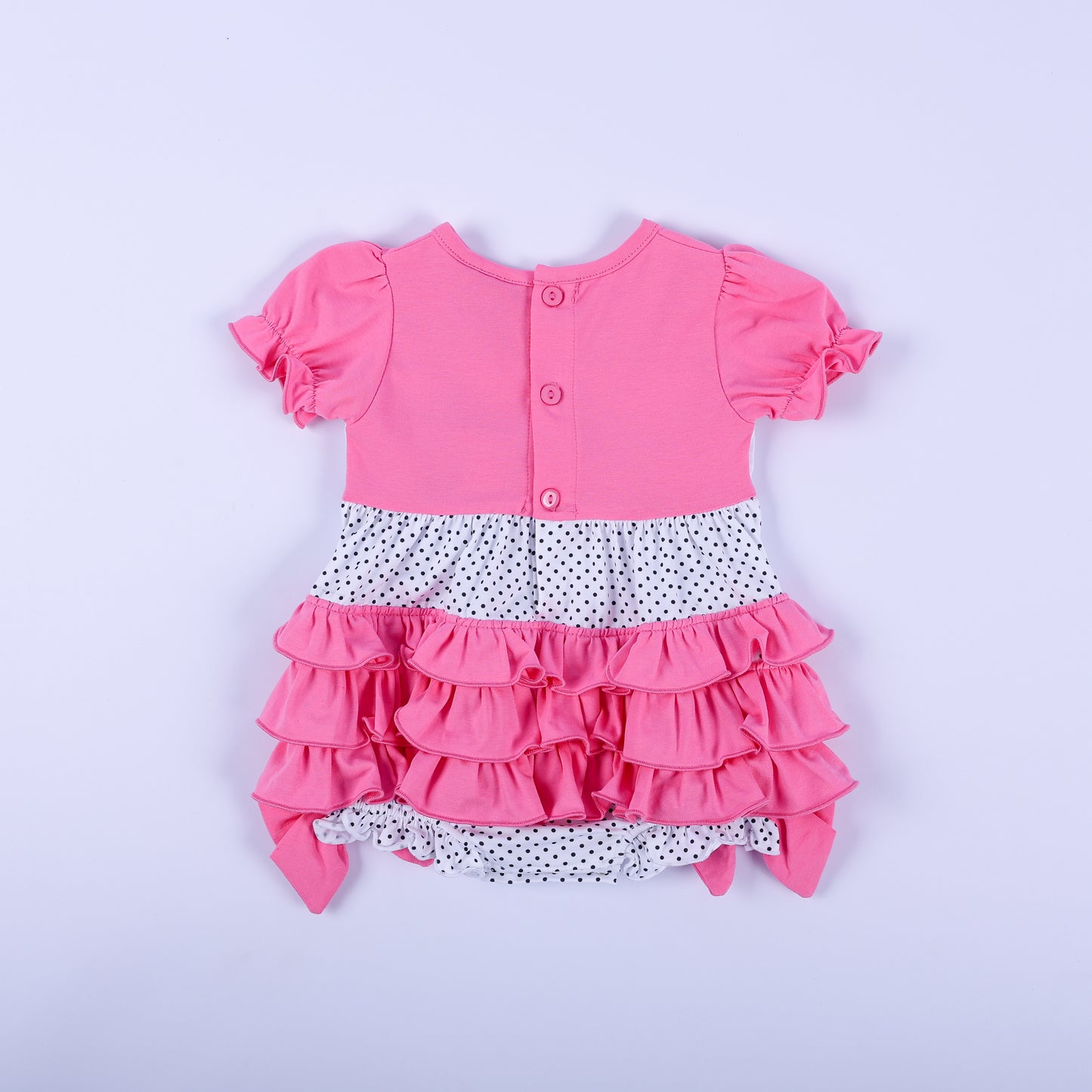 Back view of pink and polka dot hand-smocked baby girl bubble romper showing rear ruffle layers and button closure.