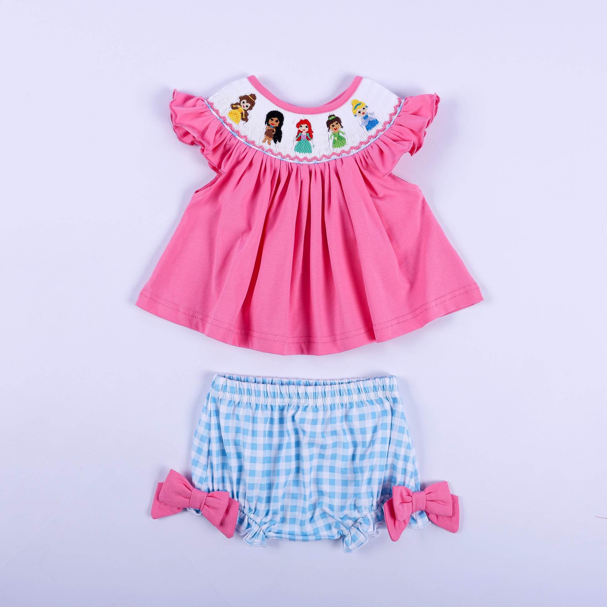 Pink princess hand-smocked knit top paired with blue gingham diaper cover bloomer set for baby girls.