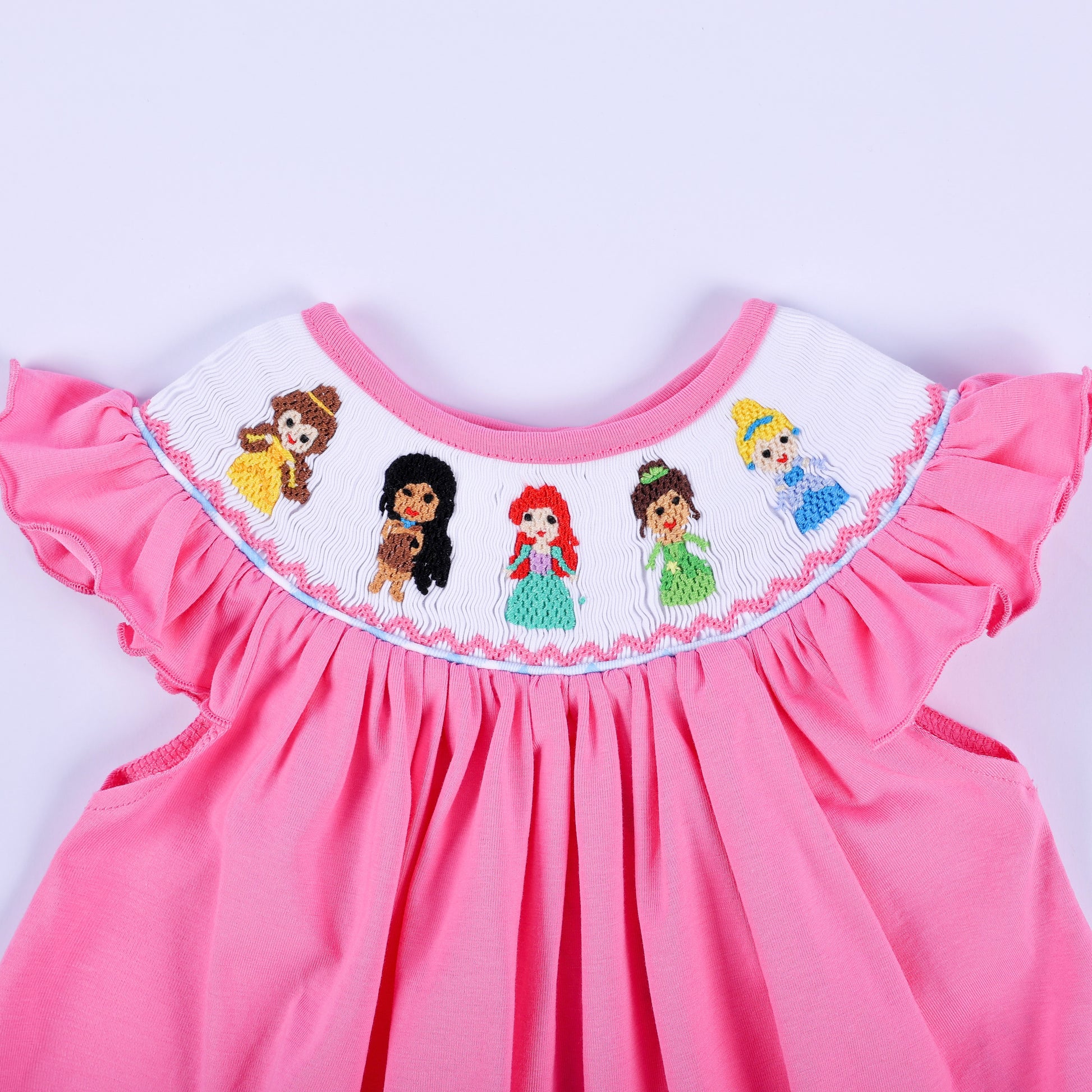 Detailed close-up of hand-smocked princess embroidery on pink knit flutter sleeve baby girl top collar.