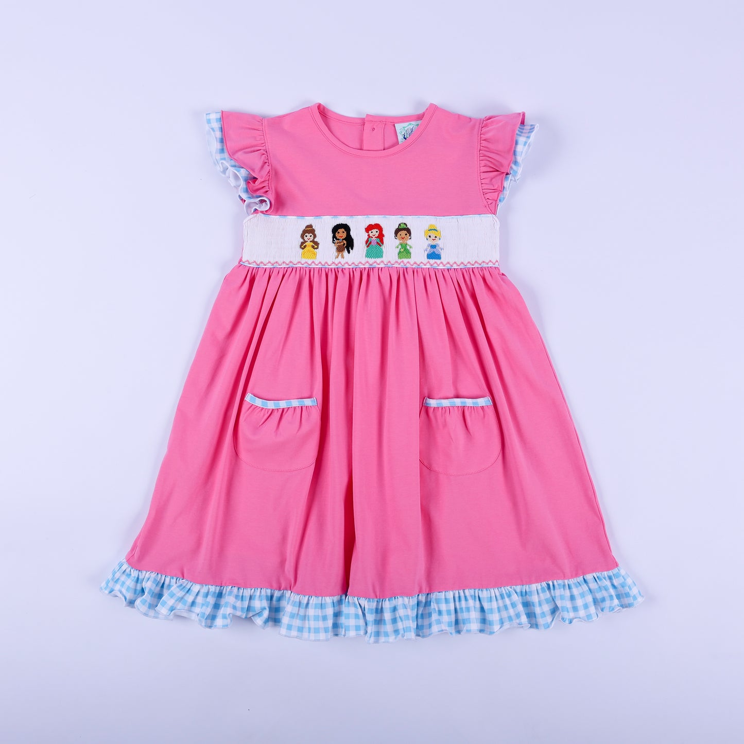 Full front view of girls pink princess knit hand smocked dress featuring blue gingham ruffle trim and pockets.