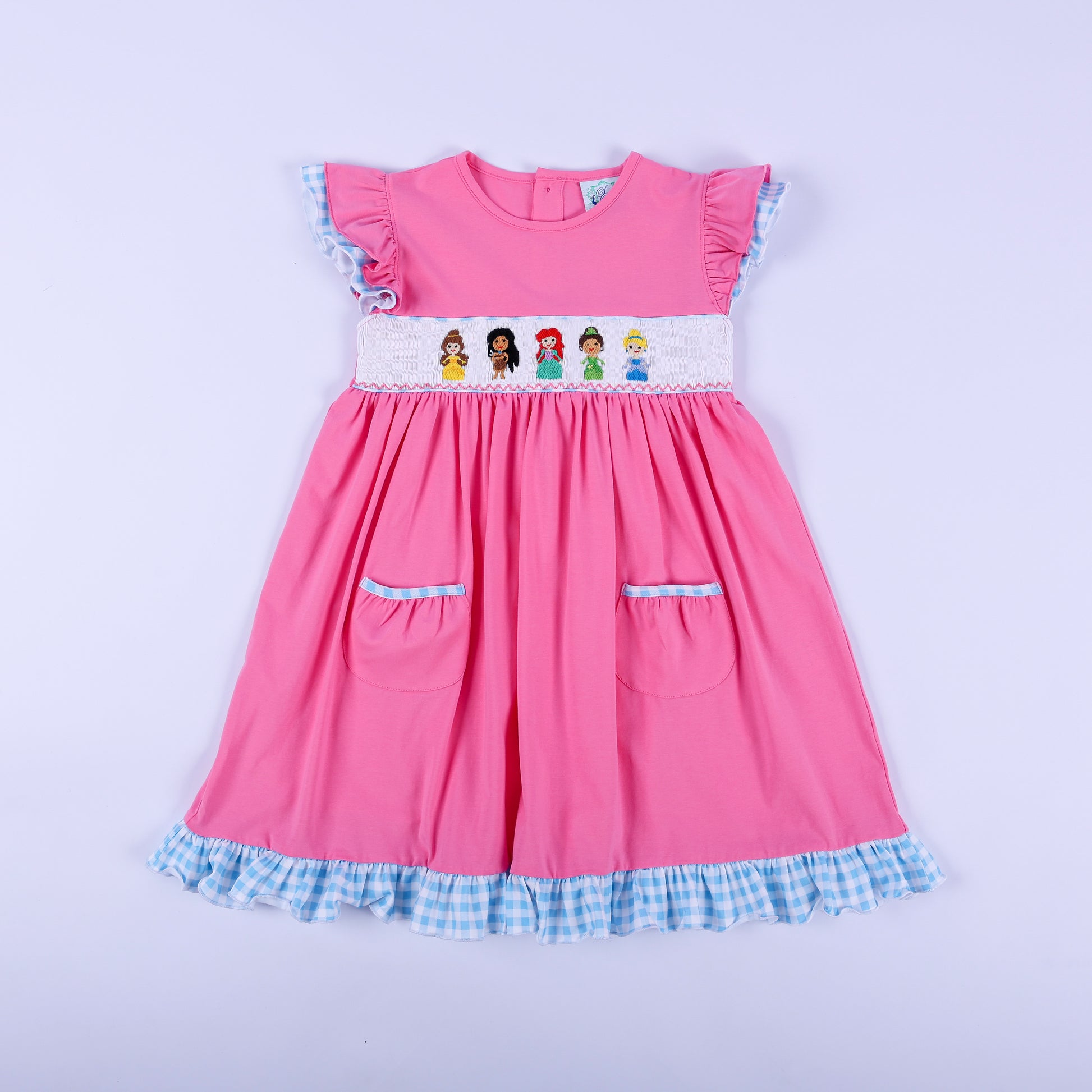 Full front view of girls pink princess knit hand smocked dress featuring blue gingham ruffle trim and pockets.