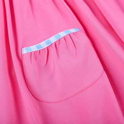 Detail of pink knit skirt pocket trimmed with blue gingham piping on hand smocked embroidered princess dress.