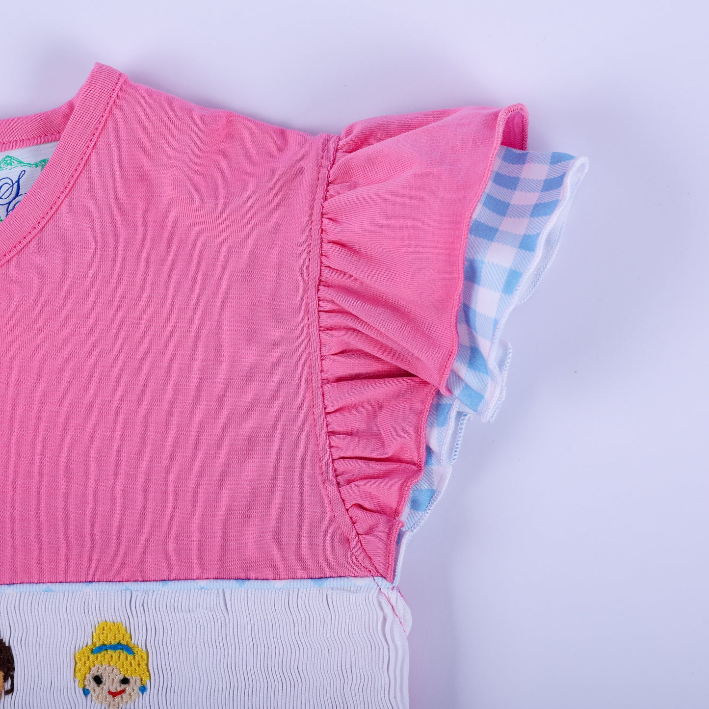 Close-up of pink flutter sleeve with layered blue gingham ruffle trim on girls hand smocked princess knit dress.