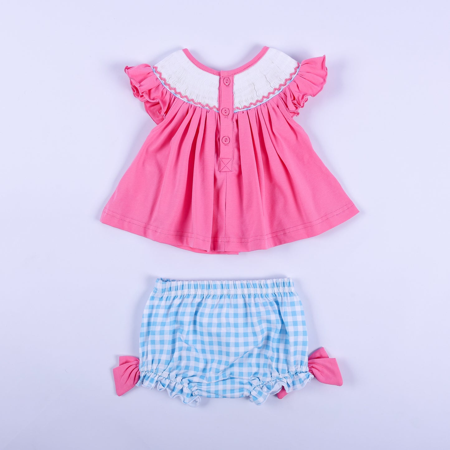 Back view of pink knit hand-smocked top with button closure and blue gingham bloomer set for baby girls.