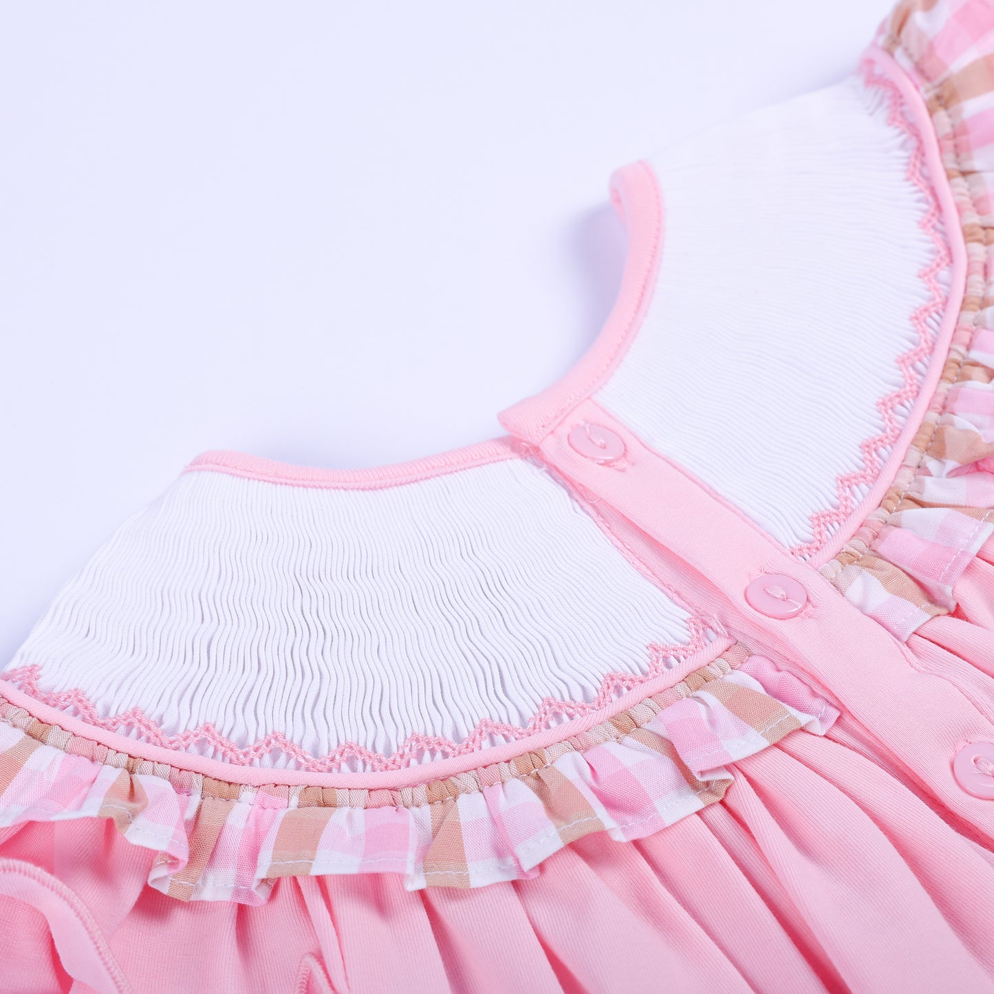 Close-up of back button closure on a pink hand-smocked baby bubble collar with pink gingham ruffle edging.