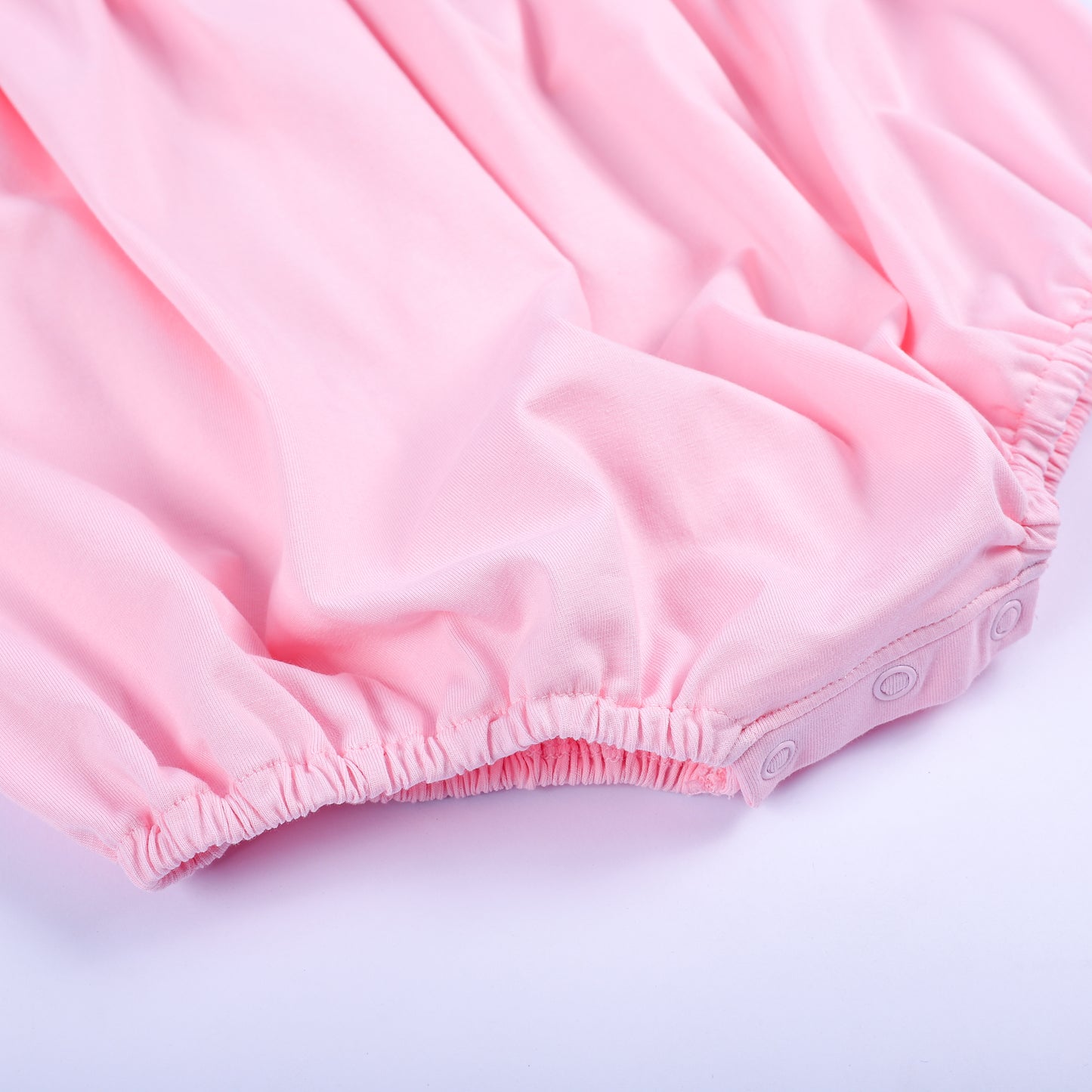 Bottom detail of a pink hand-smocked baby bubble showing secure snap closures and elasticized leg openings.