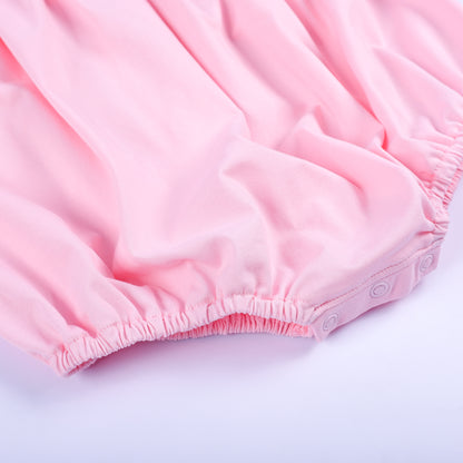 Bottom detail of a pink hand-smocked baby bubble showing secure snap closures and elasticized leg openings.