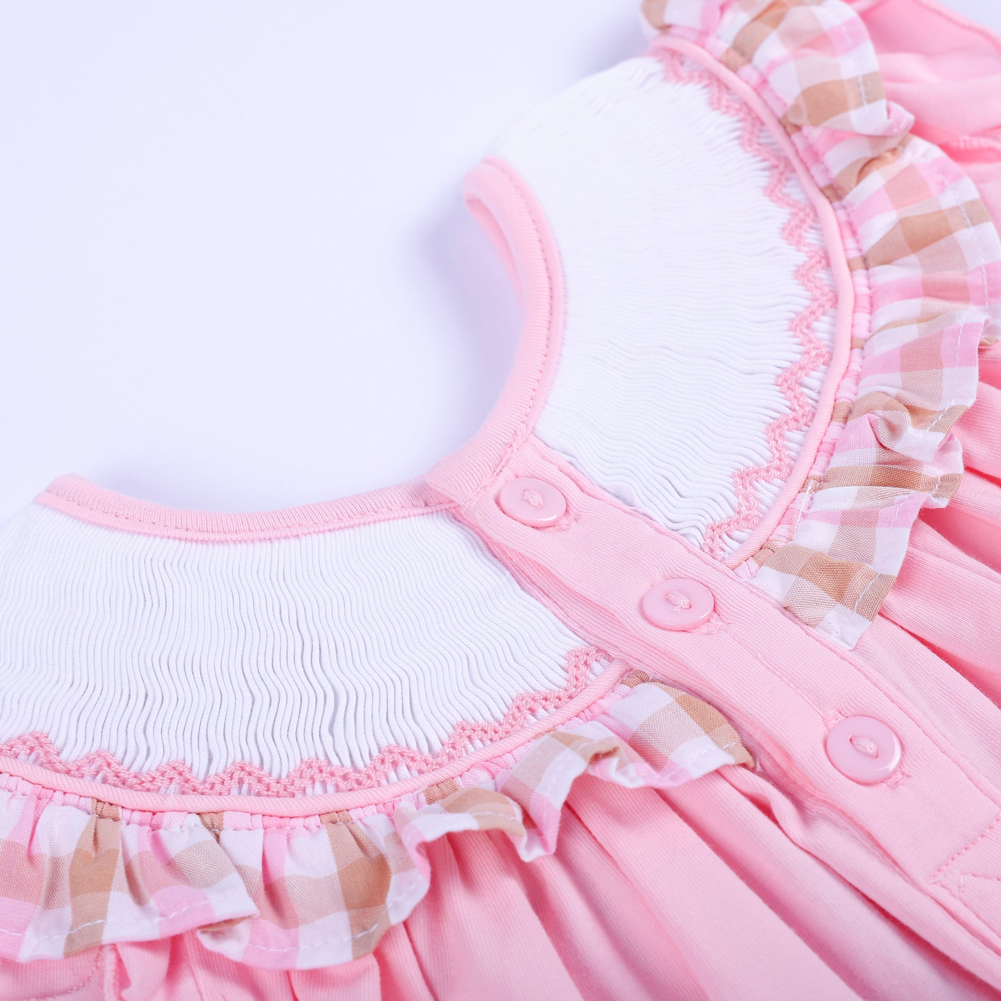 Close-up back closure view showing pink buttons and smocked neckline collar on a baby girl beach top.