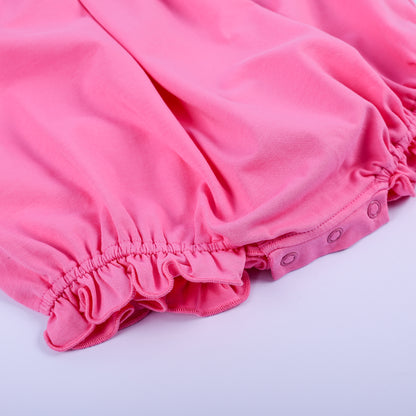Close-up of ruffled leg openings and convenient snap closure on a pink hand-smocked knit bubble romper for infants.