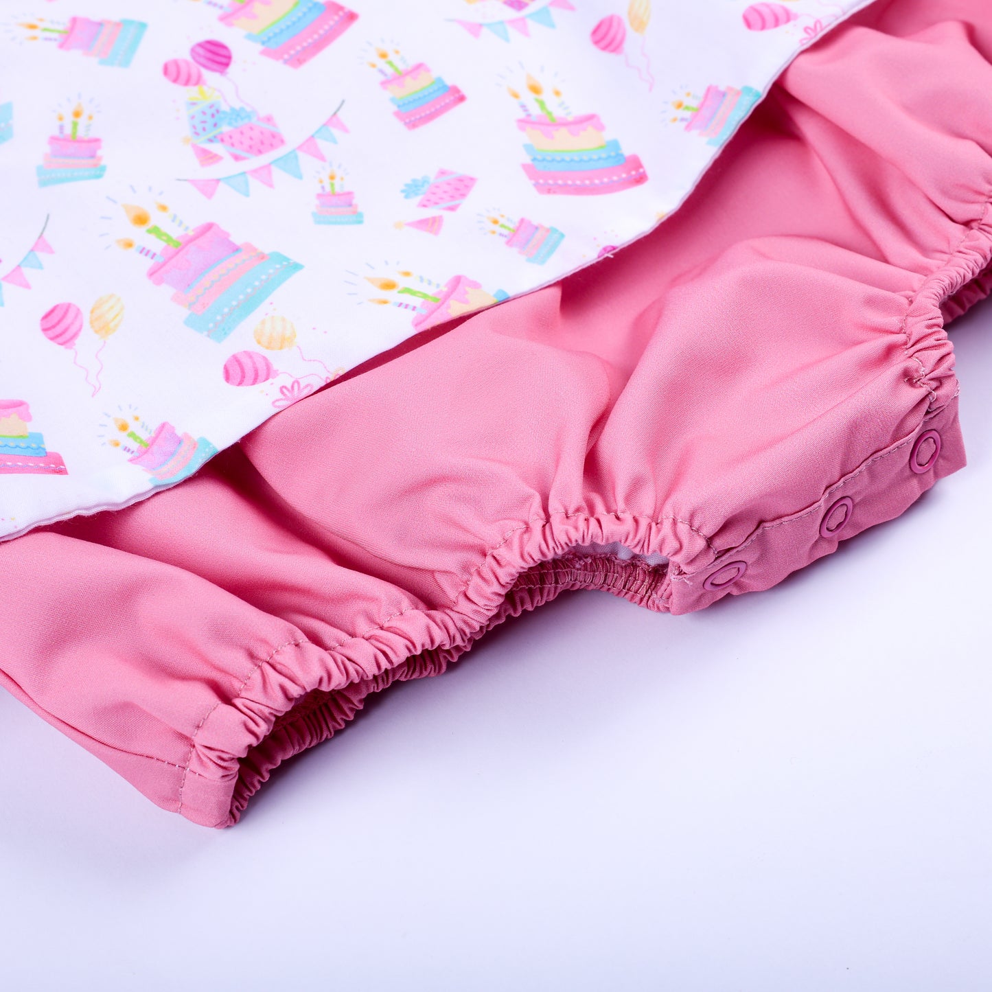 Close-up of pink bloomer bottom with convenient snap buttons on a baby girl birthday smocked bubble outfit.