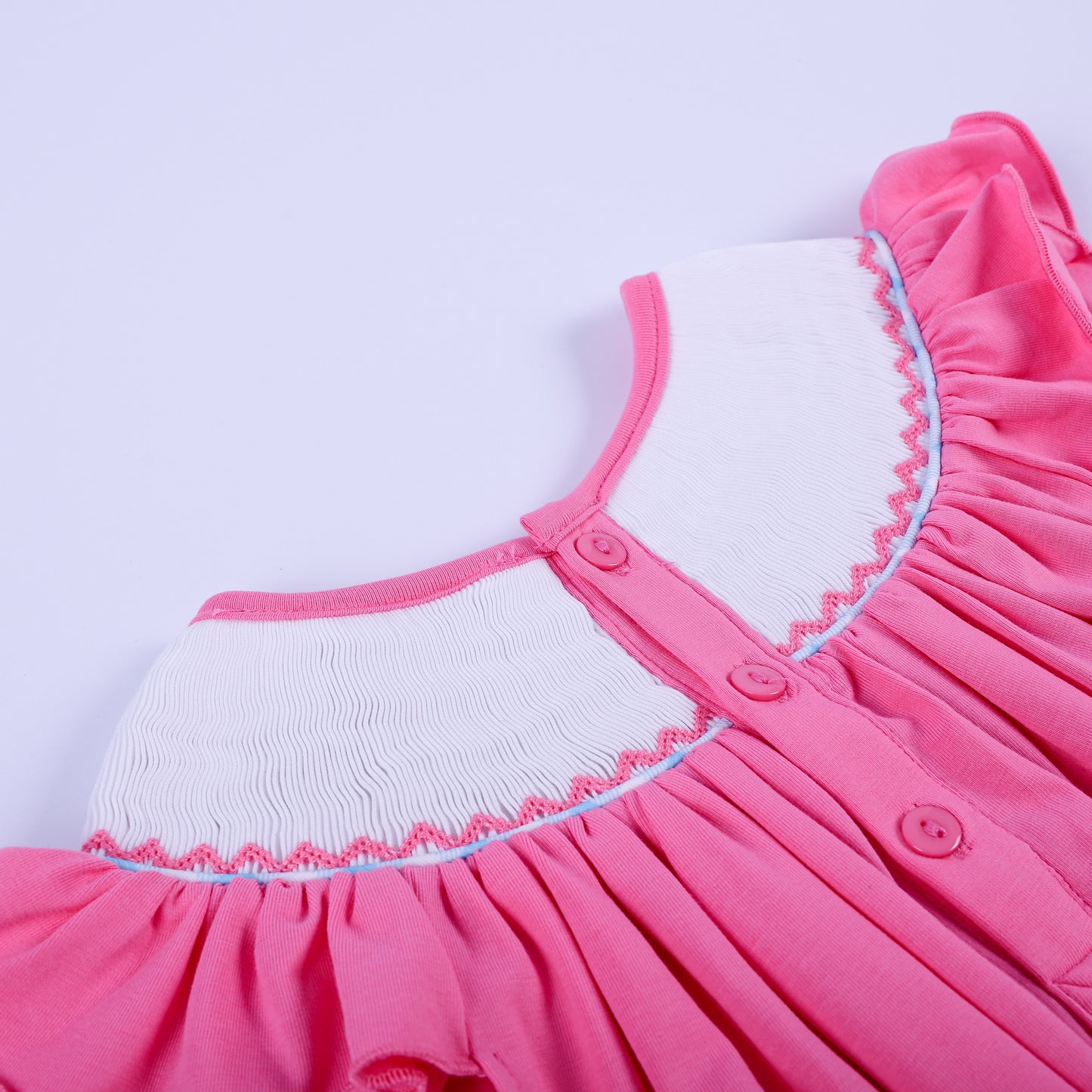Detailed back close-up showing pink buttons and delicate smocked neckline stitching on a baby girl knit bubble outfit.