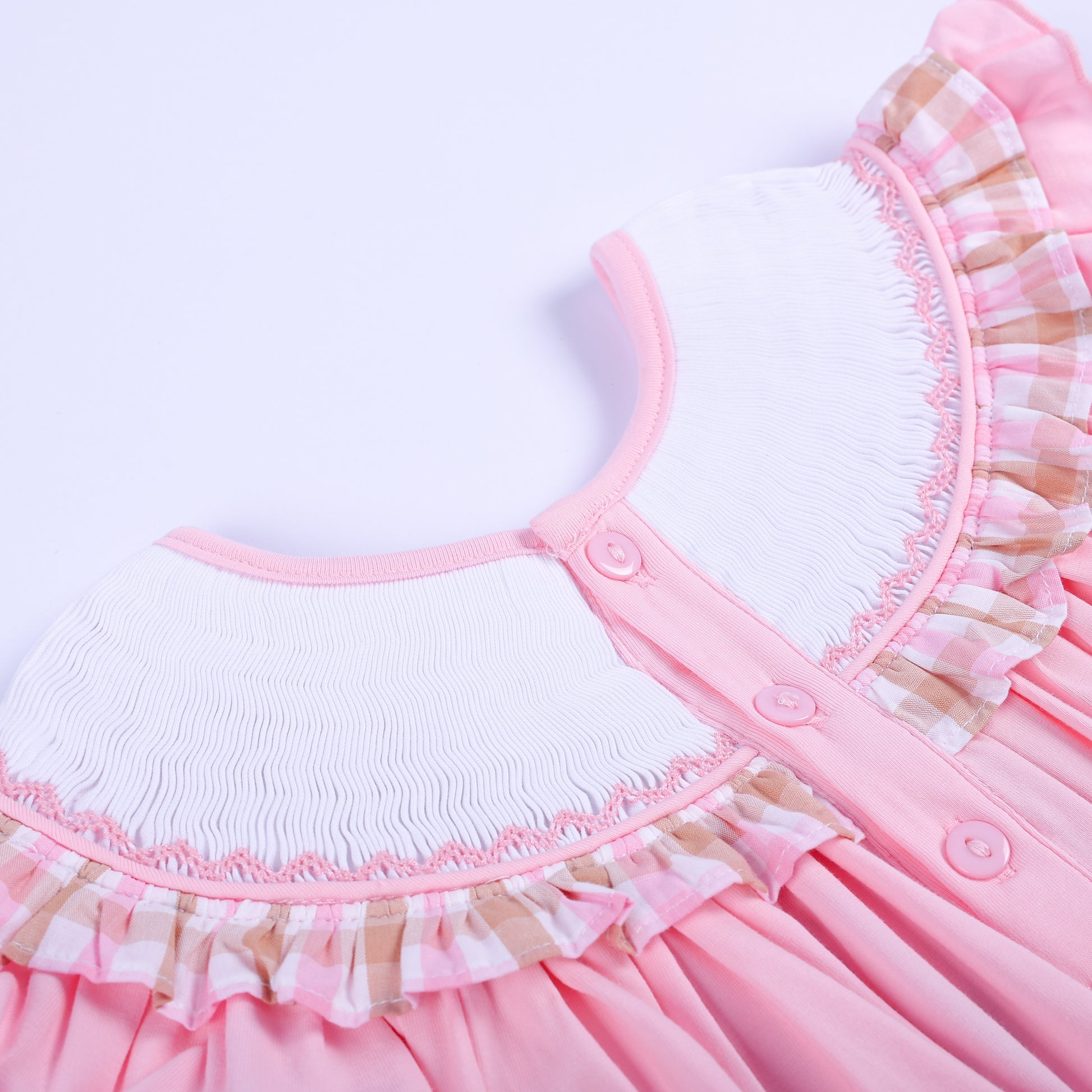 Close-up of pink button closure and smocked neckline detail on the back of a hand smocked beach dress for girls.