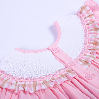 Close-up of pink button closure and smocked neckline detail on the back of a hand smocked beach dress for girls.