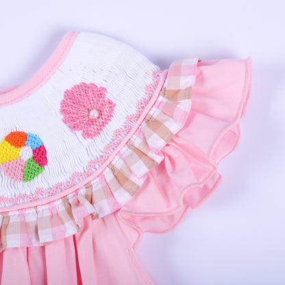 Detailed view of pink gingham ruffle sleeve and hand embroidered pink seashell on a girl's smocked beach dress.