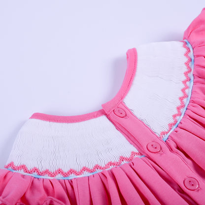 Close-up back button closure detail on pink hand-smocked knit baby girl top with ruffled neckline collar.